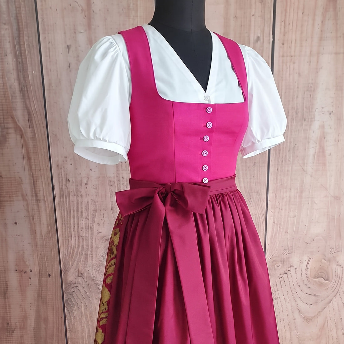 Dirndl-132 mit weißen Puffärmeln und einem großen Schleifenband, elegant präsentiert auf einem Schneiderbüste.