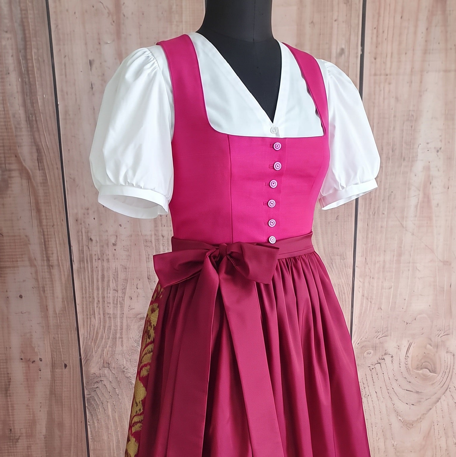 Dirndl-132 mit weißen Puffärmeln und einem großen Schleifenband, elegant präsentiert auf einem Schneiderbüste.